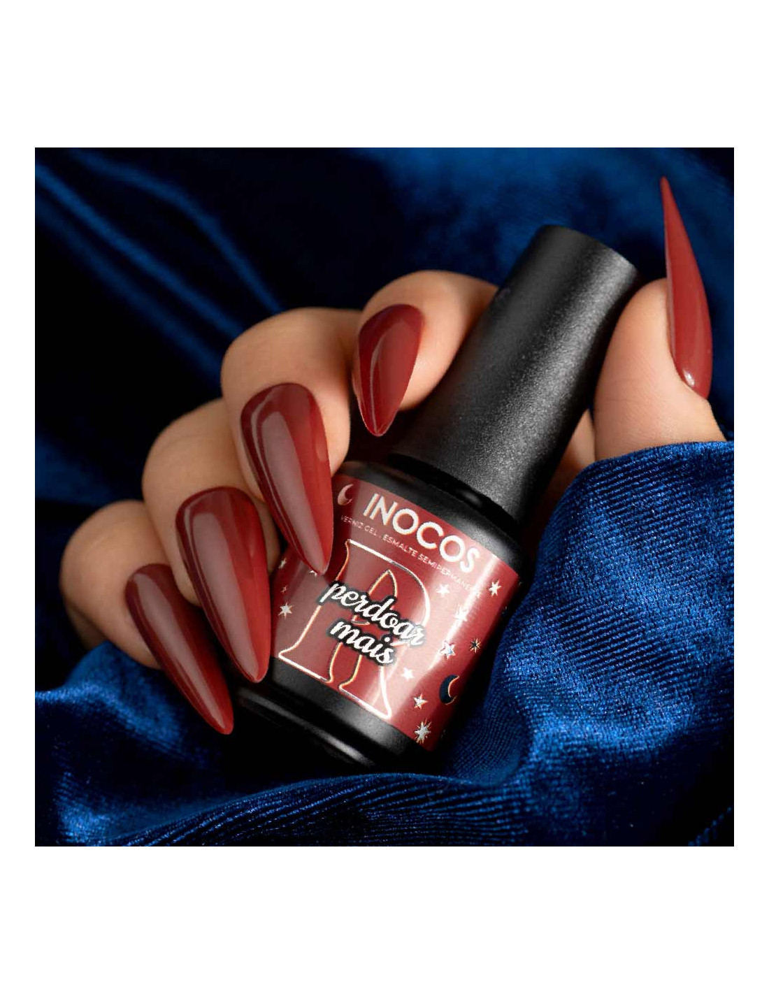 Verniz Gel Inocos A Million Dreams 15ml Perdoar Mais MD6 Unhas com verniz vermelho escuro segurando frasco de verniz gel INOCOS em fundo azul