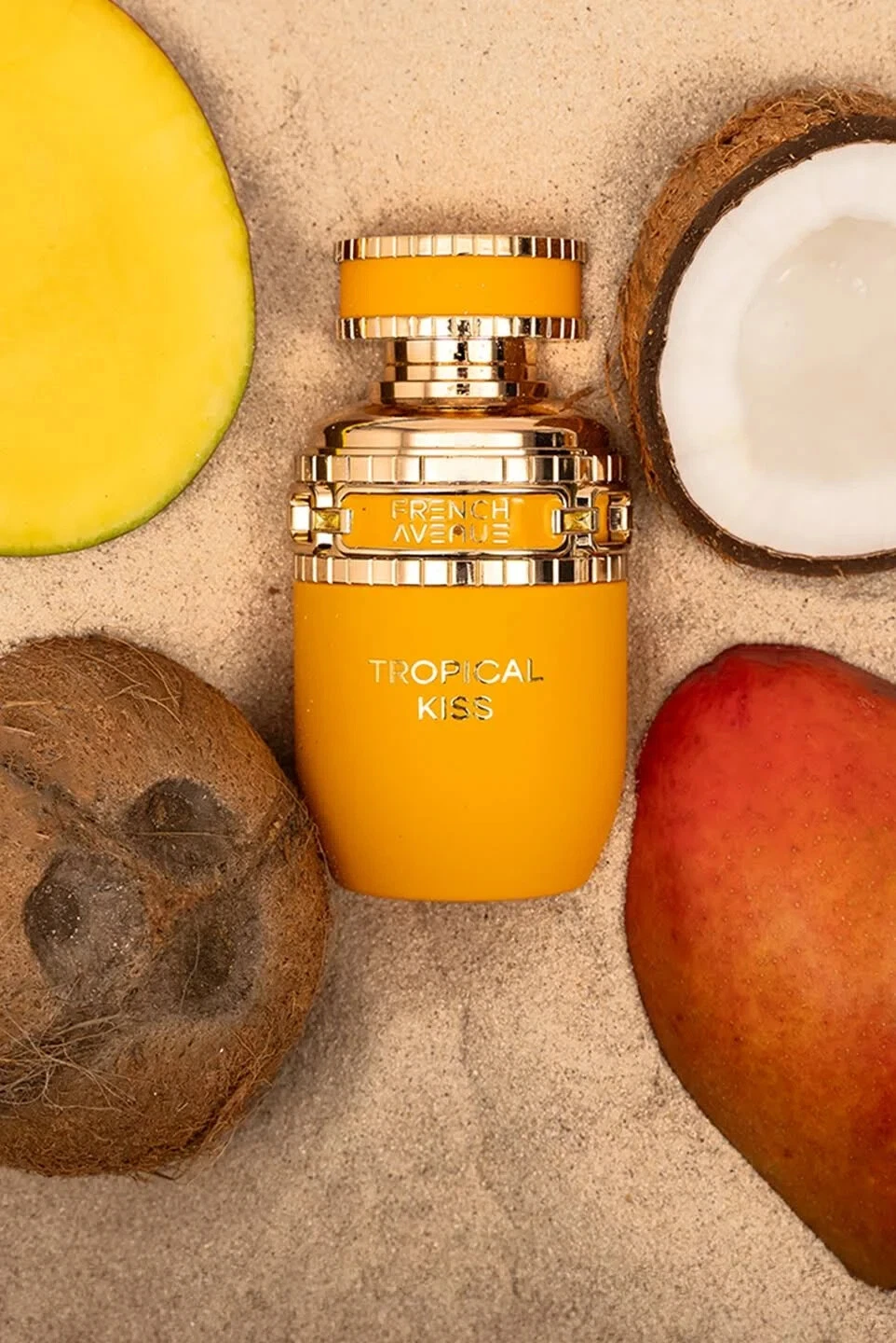 French Avenue Tropical Kiss Eau de Parfum para mulheres Frasco de perfume amarelo com detalhes dourados e texto Tropical Kiss, rodeado por frutas tropicais na areia