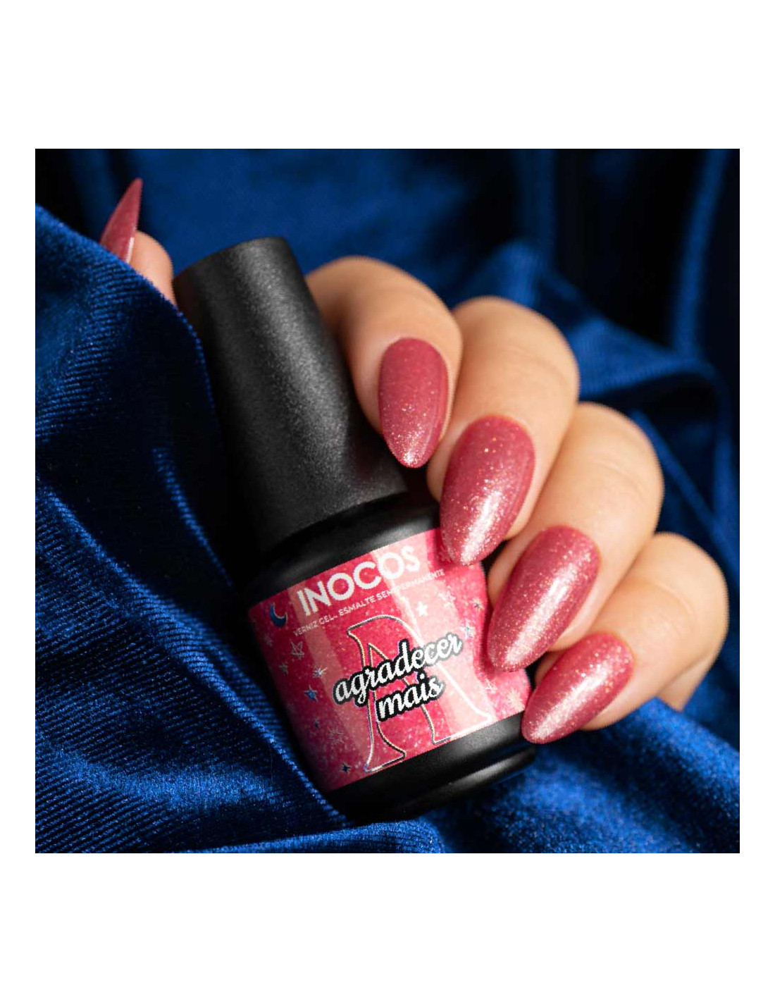 Verniz Gel Inocos A Million Dreams 15ml Agradecer Mais MD5 Frasco de verniz de unhas INOCOS rosa com glitter nas mãos, fundo de tecido azul