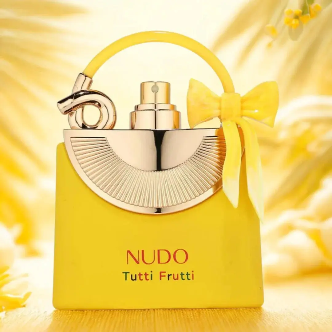 Fragrance World Nudo Tutti Fruity 100ml Frasco de perfume amarelo com detalhes dourados e laço amarelo.