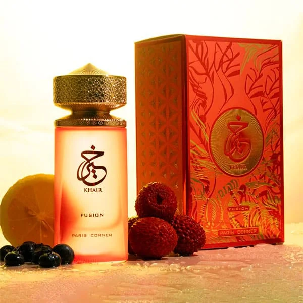 Paris Corner - Oriental Collection Khair Fusion Frasco de perfume rosado com tampa dourada e caixa vermelha ao lado de frutas variadas