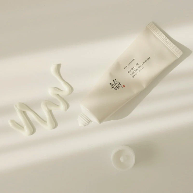 Beauty Of Joseon Relief Sun Rice +Probiotics Spf50 Sunscreen Tubo branco de creme aberto e creme espremido em superfície clara