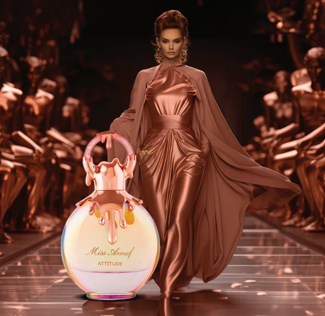 Perfume Mulher Armaf Attitude Edp 100 Ml Frasco de perfume Miss Amour ATTITUDE em passadeira de desfile com modelo vestindo vestido e capa bronze.