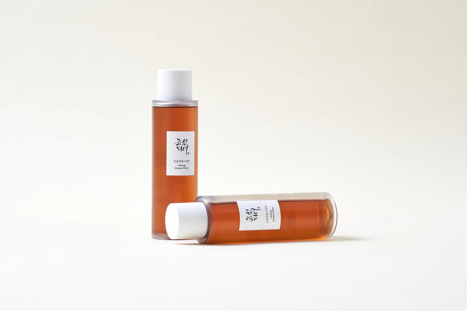 Beauty Of Joseon Ginseng Essence Water 150 Ml Duas garrafas de Ginseng Essence Water com líquido castanho e tampa branca sobre fundo branco