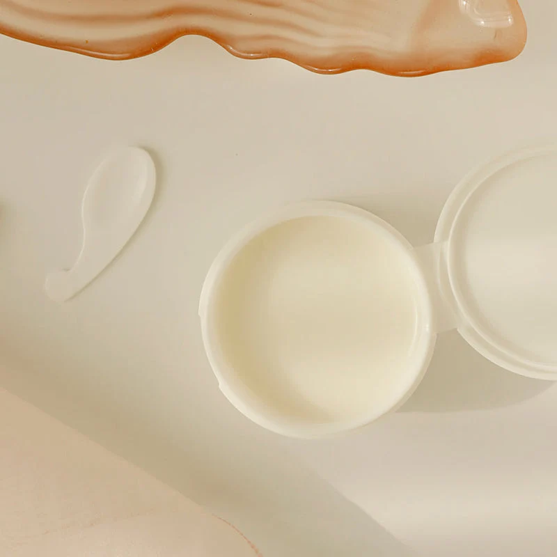 Beauty Of Joseon Radiance Cleansing Balm 100 Ml Recipiente de creme branco aberto com espátula pequena e objeto decorativo laranja