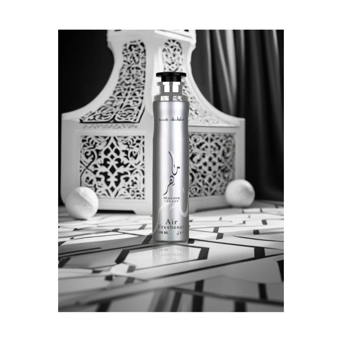 Lattafa Maahir Legacy Air Freshener 300 ml Frasco prateado de spray para ambientador com texto e fundo decorativo branco com padrão recortado
