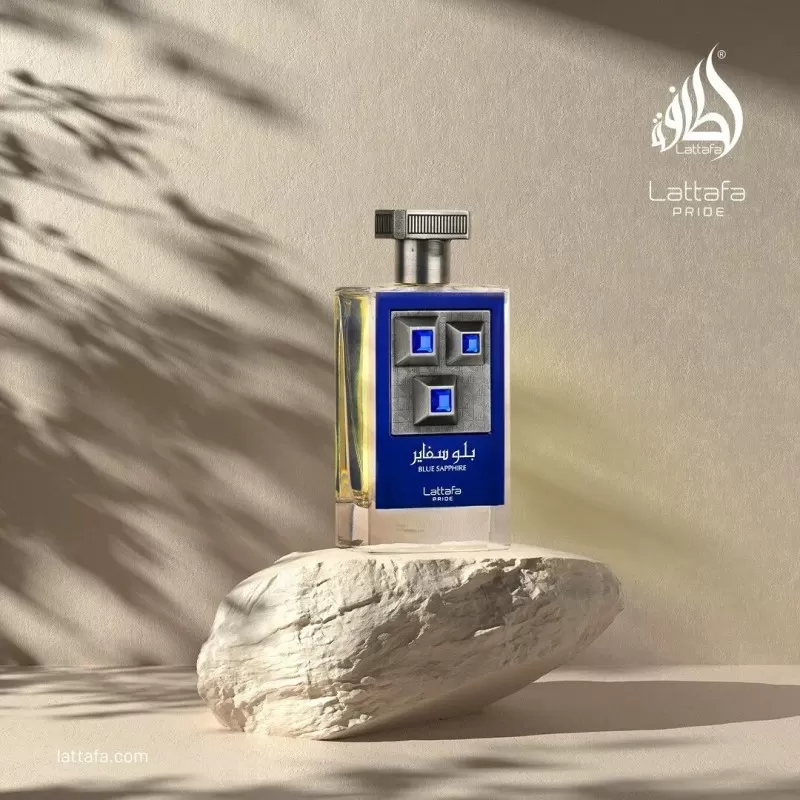 Lattafa Men's Pride Blue Sapphire EDP 100ml (Original) Frasco de perfume azul e transparente sobre pedra branca em ambiente com sombras de folhas