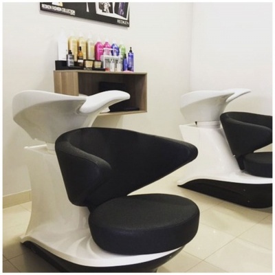 Cadeiras de cabeleireiro pretas com base branca e lavatórios brancos num salão de beleza