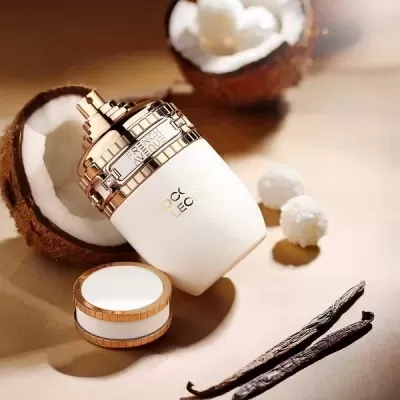 Frasco cosmético branco com detalhes dourados sobre superfície bege com cocos partidos, bolinhas brancas e vagens de baunilha