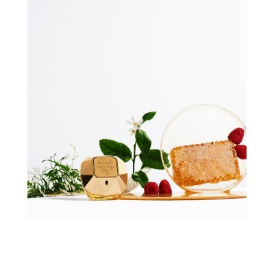 Frasco dourado de creme facial com favo de mel, framboesas e folhagem