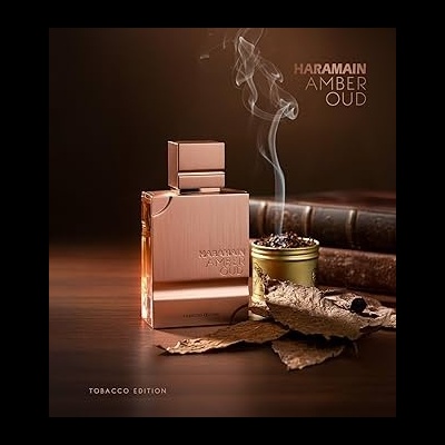 Frasco dourado do perfume Haramain Amber Oud com folhas de tabaco e recipiente metálico