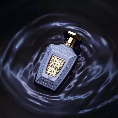 Frasco de perfume azul cinzento com tampa dourada na água