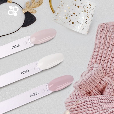 Amostras de verniz de unhas em tons suaves com roupa rosa de malha e copo decorativo