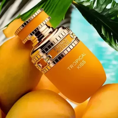 Frasco amarelo e dourado de perfume Tropical Kiss rodeado de mangas