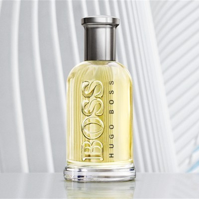 Frasco de perfume Boss Hugo Boss com líquido amarelo e tampa prateada sobre superfície branca
