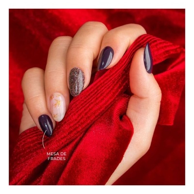 Mão com unhas decoradas segurando tecido vermelho