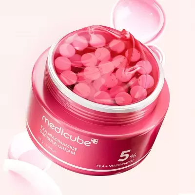 Frasco rosa com cápsulas de creme vermelhas e texto medicube TXA NIACINAMIDE CAPSULE CREAM
