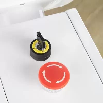 Interruptor rotativo com chave preta e botão de emergência vermelho num painel branco