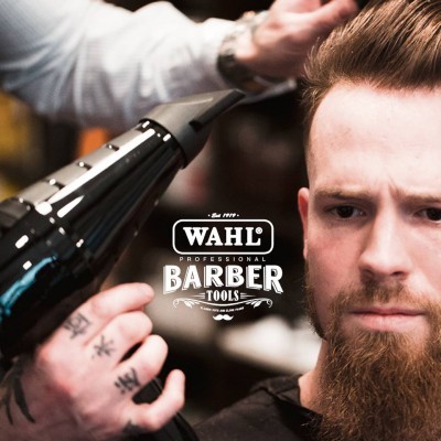 Secador de cabelo preto a secar cabelo de homem com barba castanha e logo WAHL Barber Tools
