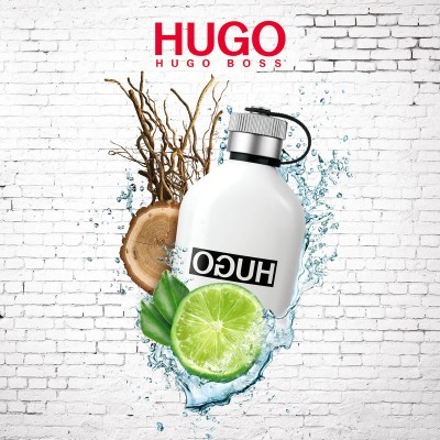 Frasco branco de perfume Hugo Boss com lima, madeira e água sobre fundo de parede branca de tijolos