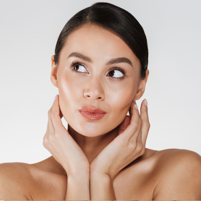 Mulher com pele lisa e bronzeada, cabelos castanho-escuros presos, mãos no pescoço, fundo branco