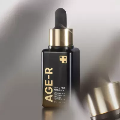Frasco preto com conta-gotas dourado e preto com texto dourado sobre fundo cinzento
