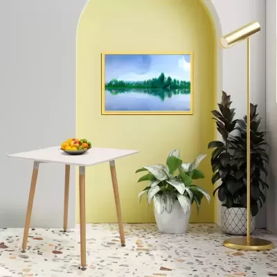 Sala com mesa branca, plantas, luminária dourada e quadro de paisagem num nicho amarelo