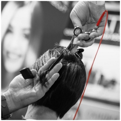 Pessoa a cortar cabelo curto e escuro com tesouras, imagem em preto e branco