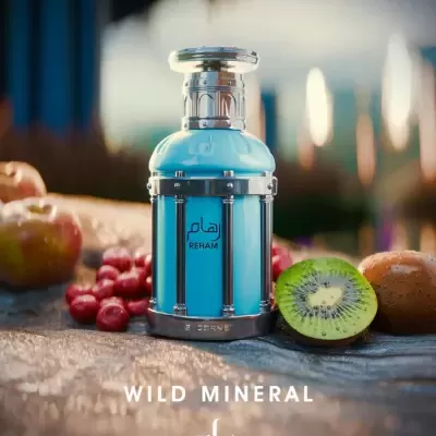 Frasco azul metálico de perfume REHAM com frutas sobre madeira