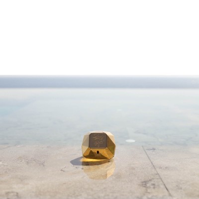 Frasco de perfume dourado facetado junto a piscina