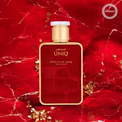 Frasco de perfume ÁRMAF ÚNIQ vermelho e dourado sobre fundo vermelho marmoreado.