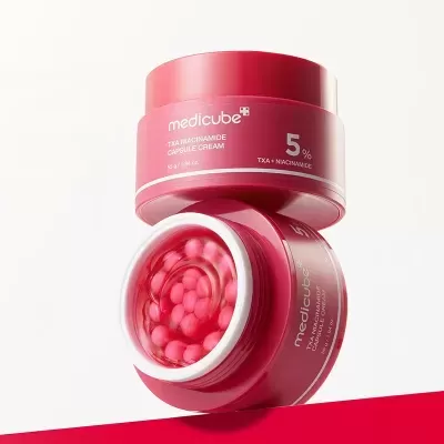 Frasco vermelho de creme Medicube com cápsulas cor-de-rosa no interior