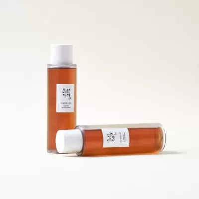 Duas garrafas de Ginseng Essence Water com líquido castanho e tampa branca sobre fundo branco