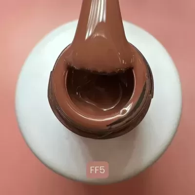 Frasco branco de verniz de unhas com verniz castanho e código FF5 num fundo rosa