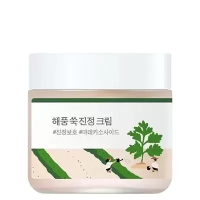 Frasco de creme branco com rótulo em coreano e ilustração de planta e personagens.