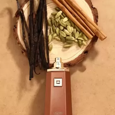 Frasco de perfume castanho com paus de canela, vagens de baunilha e cardamomo em fatia de madeira