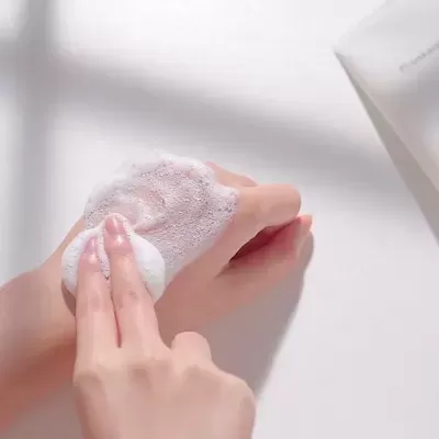 Mãos aplicando espuma branca com embalagem branca ao lado