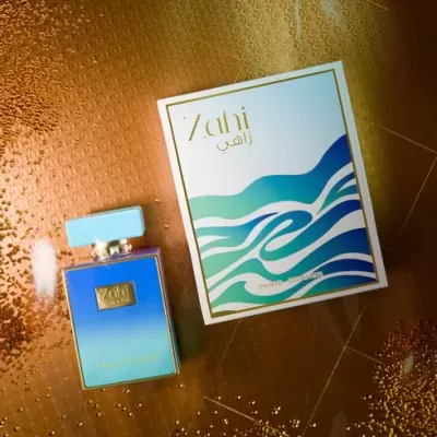 Frasco de perfume azul com caixa branca ao lado sobre fundo dourado