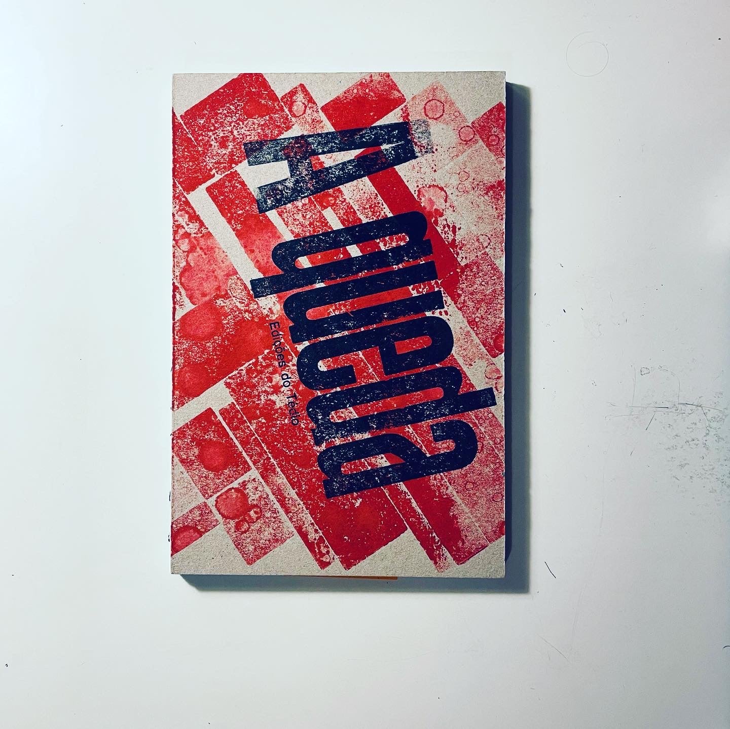 A Queda Livro com capa vermelha e bege com texto azul