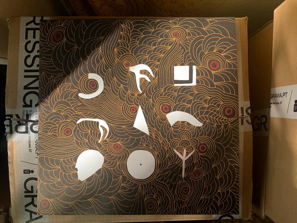 Arnaldo Trindade lê Arnaldo Trindade Caixa de cartão decorada com padrão abstrato preto, dourado e vermelho com formas brancas recortadas