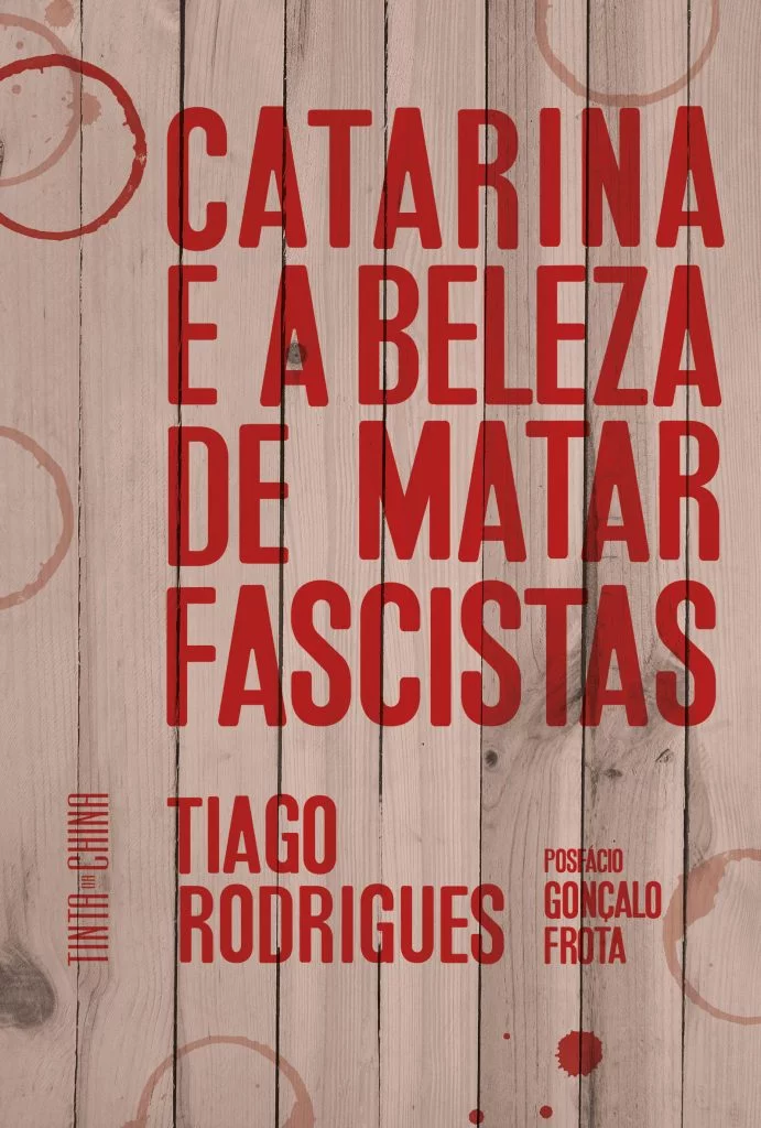 CATARINA E A BELEZA DE MATAR FASCISTAS Capa de livro com texto vermelho sobre fundo de madeira clara com manchas e anéis vermelhos