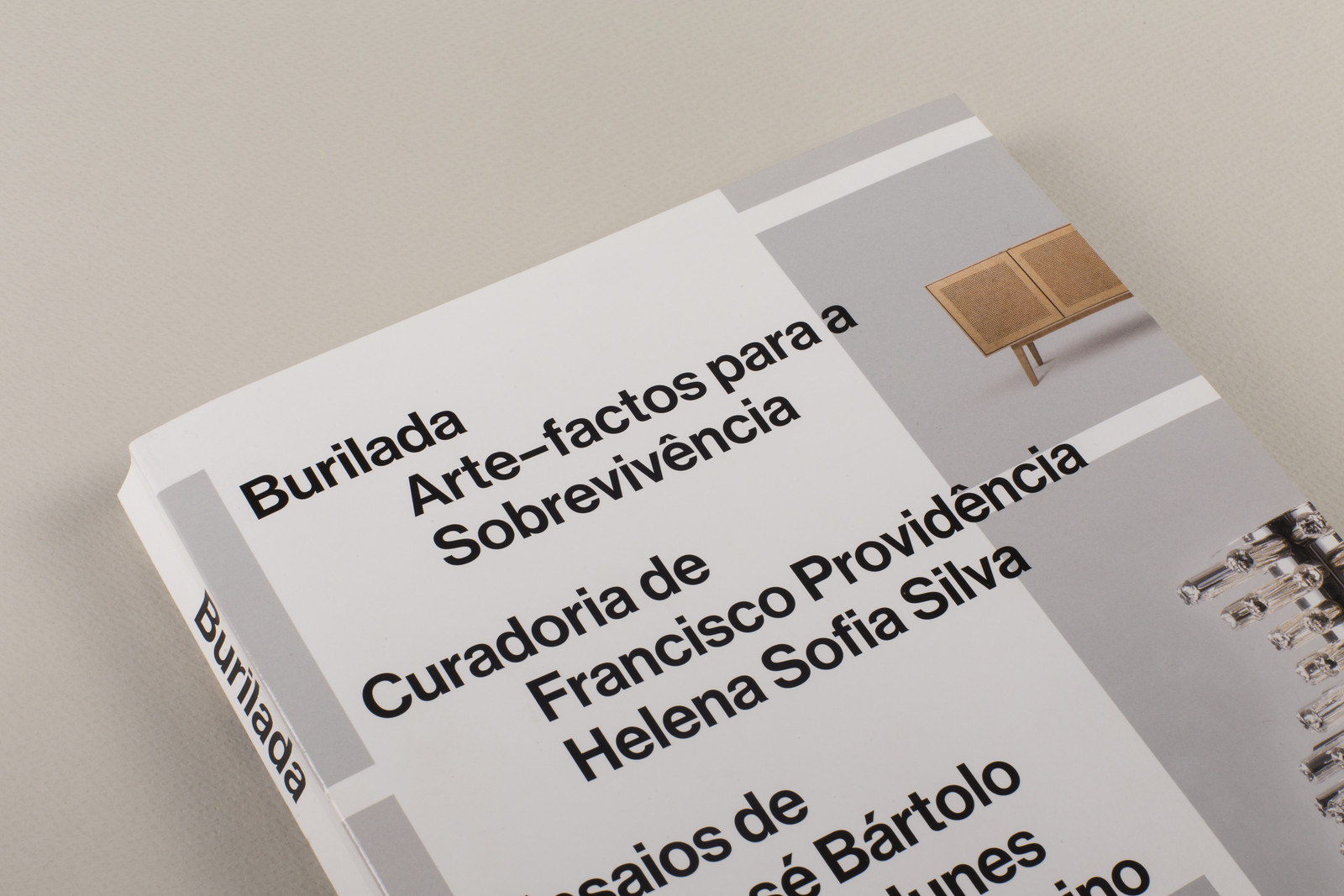 Burilada Livro branco com texto em preto e imagem parcial de móvel e utensílios na capa.