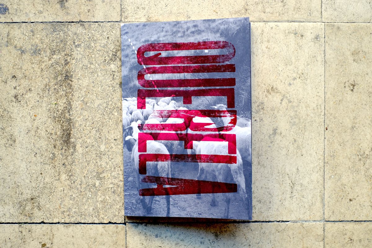 Querela #2 Livro com capa cinza com montanhas e texto vermelho vertical OMERAL ALL IZ