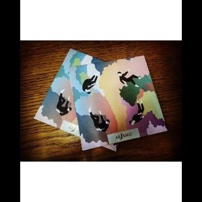 Capas coloridas com ilustração de pessoas a cair e palavra ABISMO em fundo de madeira