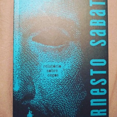 Capa de livro preta e azul com rosto ilustrado e texto Ernesto Sabato