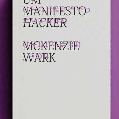 Livro branco com texto preto e lilás, título 'UM MANIFESTO HACKER MCKENZIE WARK' sobre fundo roxo