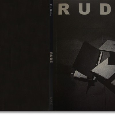 Caixa de livro preto com o título RUDE em letras brancas e livros cinza abertos e fechados