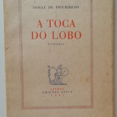Capa de livro antigo 'A TOCA DO LOBO' de Tomaz de Figueiredo, capa em papel envelhecido com texto vermelho e preto.