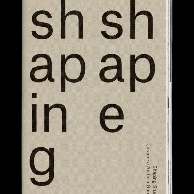 Livro com capa dura bege claro com texto preto 'shaping shape' e 'Sharing shape Curadora Andreia Garcia'