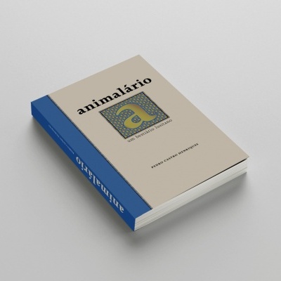 Livro animalário com capa bege e azul sobre fundo cinzento
